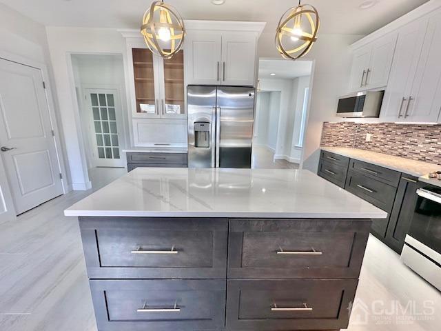 9 Melrose Ave, Sayreville, NJ 08879 - kitchen featuring decorative light fixtures, appliances with stainless steel finishes, tasteful backsplash, and white cabinetry