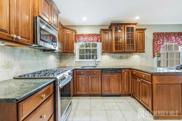 318 Ambrose Ave, Middlesex, NJ 08846 - kitchen with stainless steel appliances, a peninsula, brown cabinetry, dark stone countertops, and light tile patterned floors