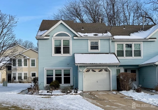 view of front of property featuring a garage, concrete driveway, and roof with shingles