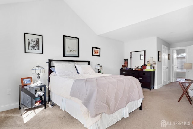 carpeted bedroom featuring lofted ceiling and connected bathroom