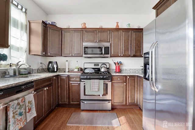 kitchen featuring stainless steel appliances, plenty of natural light, light hardwood / wood-style floors, and sink