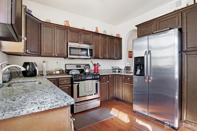 kitchen featuring sink, light hardwood / wood-style flooring, dark brown cabinets, and appliances with stainless steel finishes