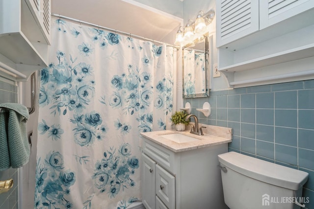 bathroom with toilet, tile walls, vanity, and curtained shower