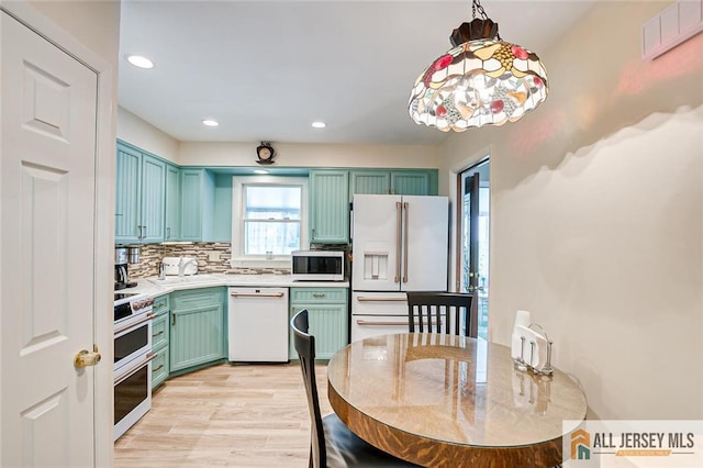kitchen with white appliances, light countertops, recessed lighting, decorative backsplash, and green cabinetry