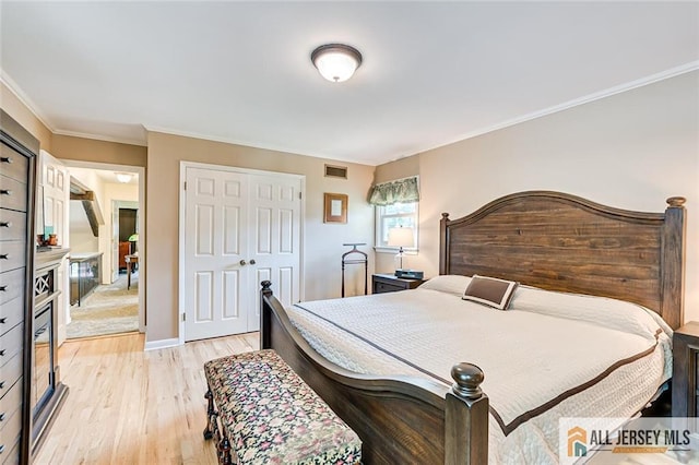 bedroom featuring light wood-type flooring, a closet, and crown molding