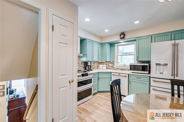 kitchen featuring white appliances, light countertops, light wood-type flooring, tasteful backsplash, and green cabinets