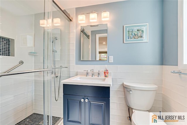 full bathroom featuring tile walls, a shower stall, toilet, vanity, and wainscoting
