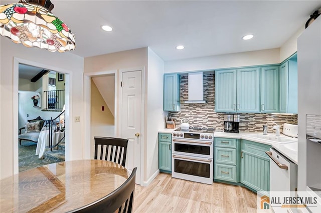 kitchen featuring double oven range, white dishwasher, decorative backsplash, light countertops, and light wood-style floors