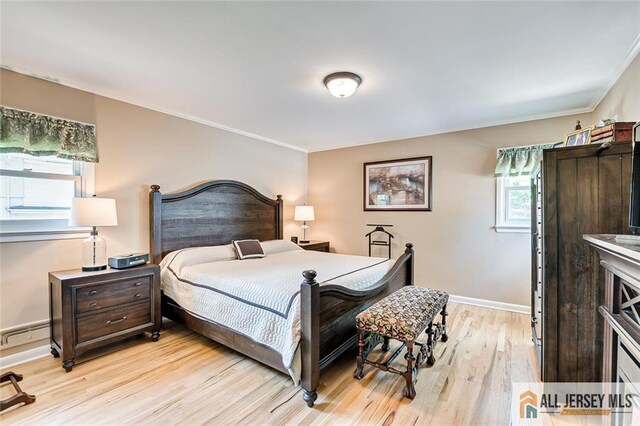 bedroom with light wood finished floors, crown molding, baseboards, and baseboard heating