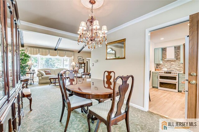 dining room with a chandelier, ornamental molding, and light colored carpet