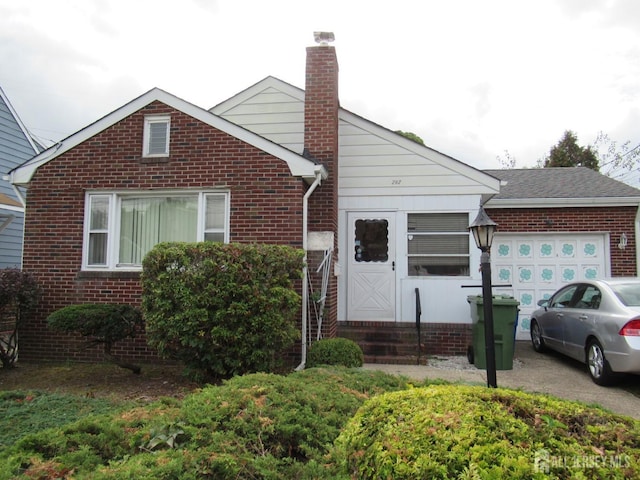 view of front of property with a garage, brick siding, driveway, and a chimney