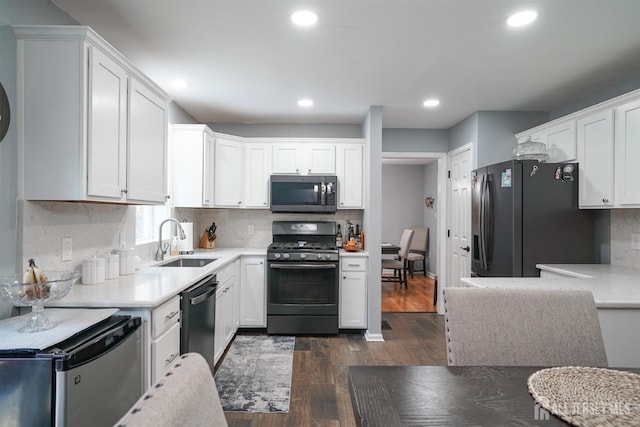 kitchen with white cabinets, light countertops, a sink, black appliances, and dark wood-style flooring