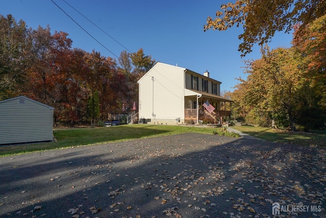 back of house with an outdoor structure, a yard, a porch, and a chimney