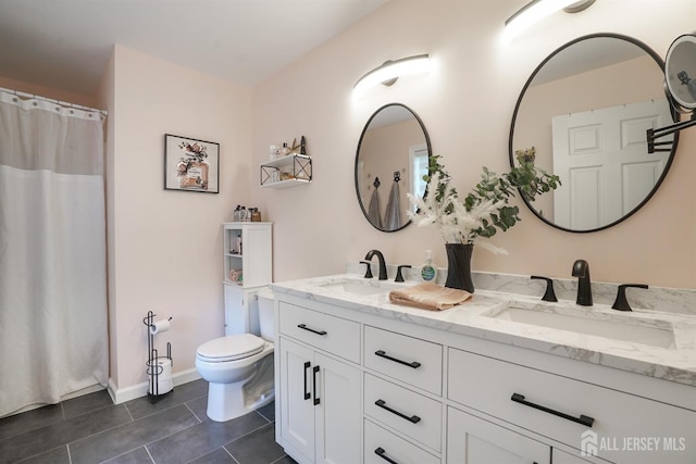 bathroom with toilet, vanity, and tile patterned floors