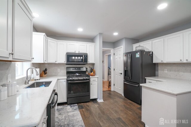 kitchen featuring dark wood-type flooring, white cabinets, sink, appliances with stainless steel finishes, and light stone counters