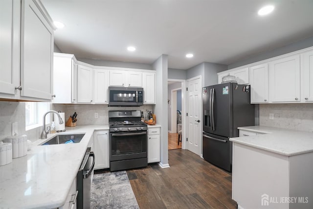 kitchen featuring stainless steel appliances, a sink, dark wood-style flooring, backsplash, and white cabinetry