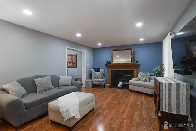living room featuring a fireplace with flush hearth, wood finished floors, and recessed lighting