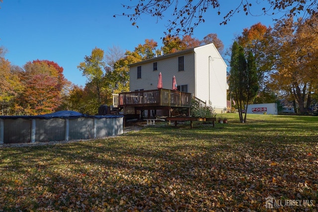 back of property featuring a wooden deck, a covered pool, and a yard