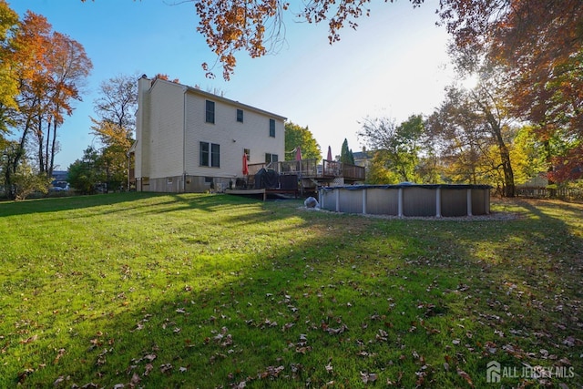 back of house featuring a chimney, an outdoor pool, a yard, and a deck
