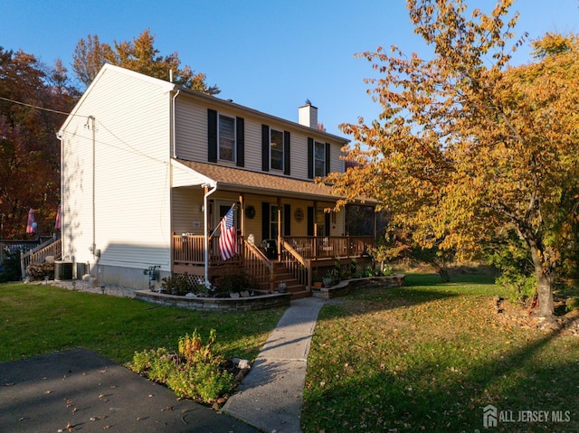 traditional-style home featuring a chimney, a front lawn, a porch, cooling unit, and stairs