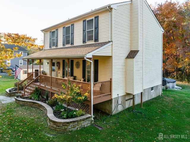 view of front of house with a front lawn, roof with shingles, and a porch