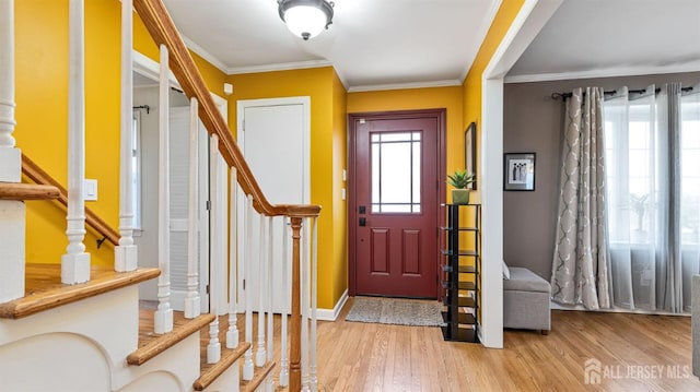 entrance foyer with stairs, baseboards, light wood-style flooring, and crown molding