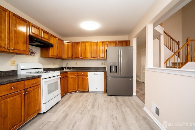 kitchen featuring light wood-type flooring, sink, white appliances, and decorative backsplash