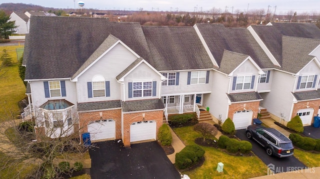 view of front of home featuring brick siding, a garage, driveway, and roof with shingles