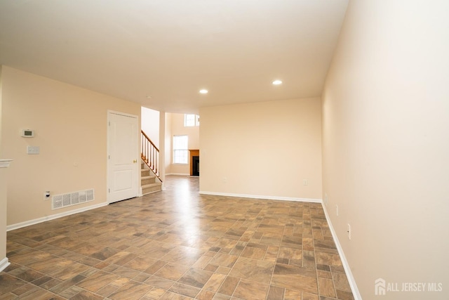 spare room with stairs, a fireplace, visible vents, and baseboards