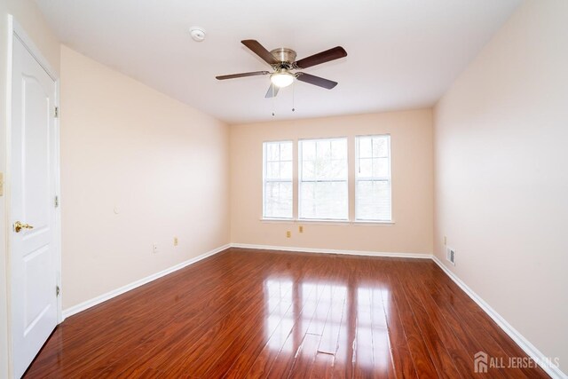 spare room with dark wood-type flooring and ceiling fan