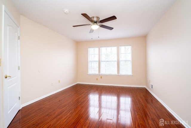 unfurnished room featuring ceiling fan, visible vents, baseboards, and wood finished floors