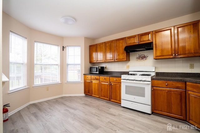 kitchen with tasteful backsplash, white gas range, and light wood-type flooring