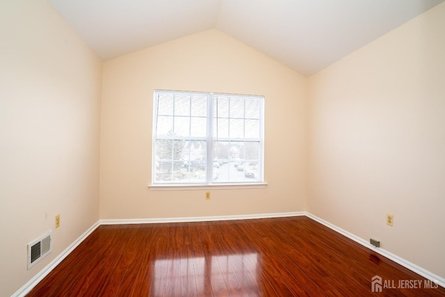 spare room with visible vents, baseboards, lofted ceiling, and wood finished floors