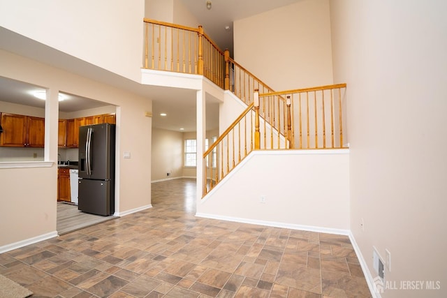 interior space with white dishwasher, stainless steel fridge, and a high ceiling