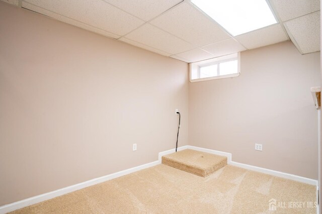 basement with a paneled ceiling and carpet