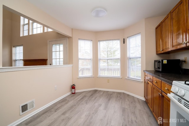 kitchen featuring white range with gas stovetop, brown cabinetry, visible vents, and light wood finished floors