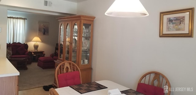carpeted dining space featuring visible vents