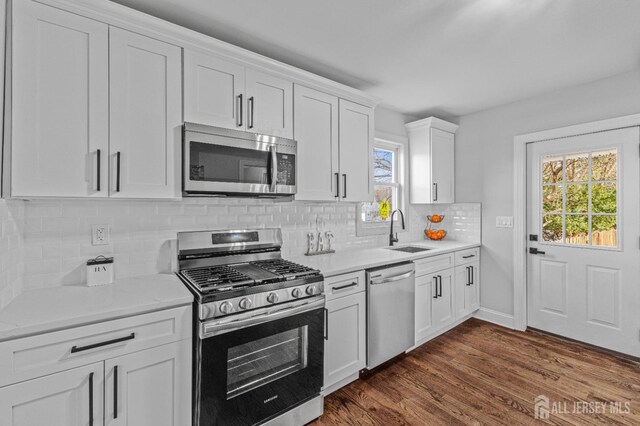 kitchen with tasteful backsplash, sink, stainless steel appliances, and white cabinetry