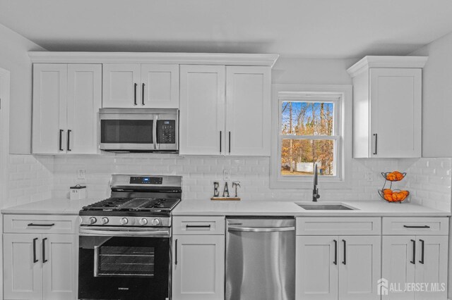 kitchen featuring tasteful backsplash, sink, stainless steel appliances, and white cabinetry