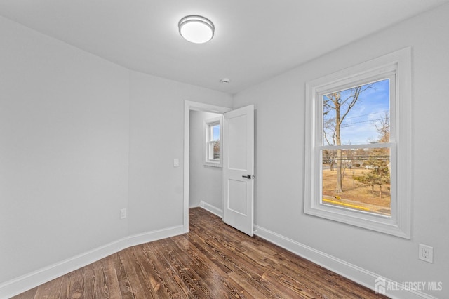 spare room with dark wood-type flooring and a wealth of natural light