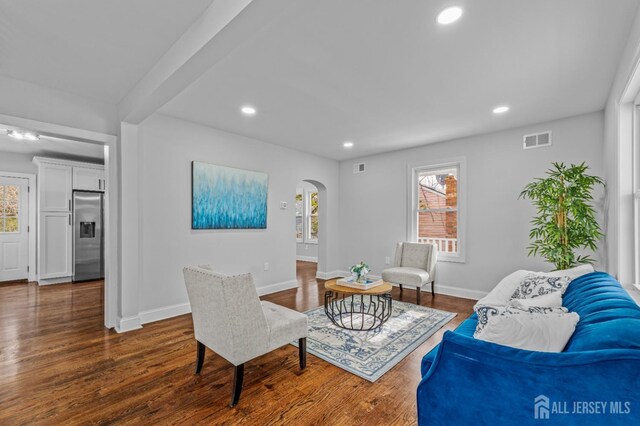 living room with beam ceiling and dark wood-type flooring