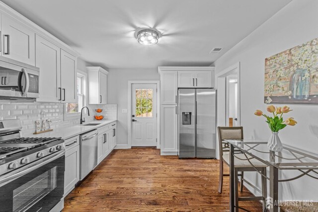 kitchen featuring decorative backsplash, sink, stainless steel appliances, and white cabinetry