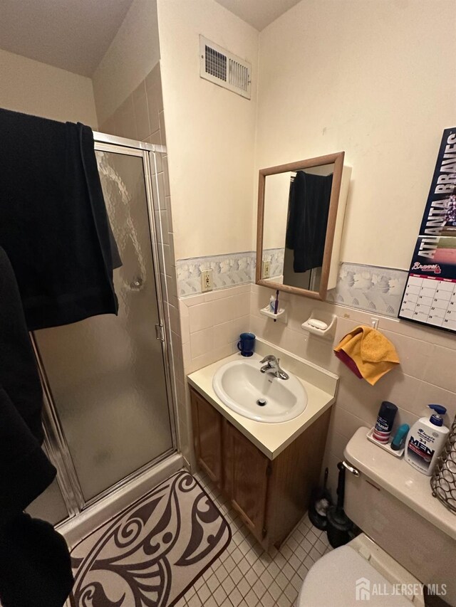 4215 Birchwood Ct, North Brunswick, NJ 08902 - bathroom featuring tile walls, tile patterned floors, toilet, a stall shower, and a wainscoted wall