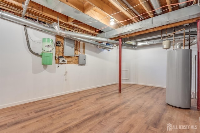 unfinished below grade area with electric panel, gas water heater, baseboards, and wood finished floors