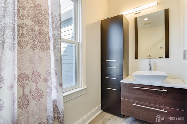 bathroom featuring a healthy amount of sunlight, vanity, baseboards, and wood finished floors