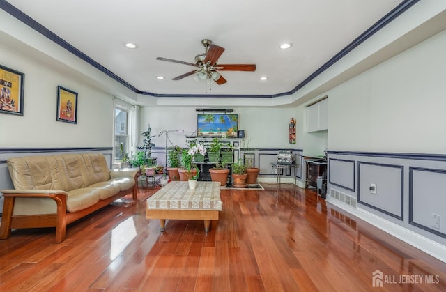 living room featuring a wainscoted wall, ornamental molding, wood finished floors, recessed lighting, and a decorative wall