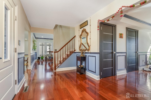 foyer with visible vents, baseboards, wood finished floors, and stairs