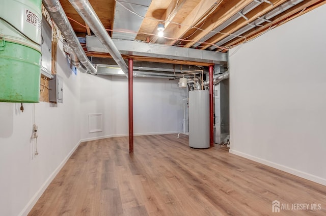 unfinished basement featuring baseboards, wood finished floors, and water heater