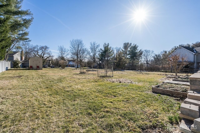 view of yard with a vegetable garden, an outdoor structure, a shed, and fence