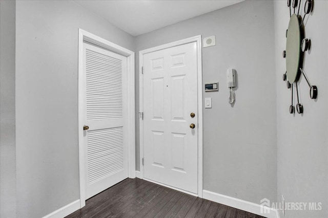 foyer entrance featuring baseboards and dark wood-style flooring